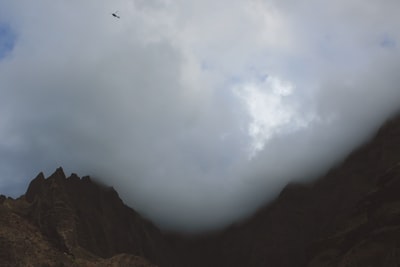 一架直升机飞过滚滚云层山地景观
